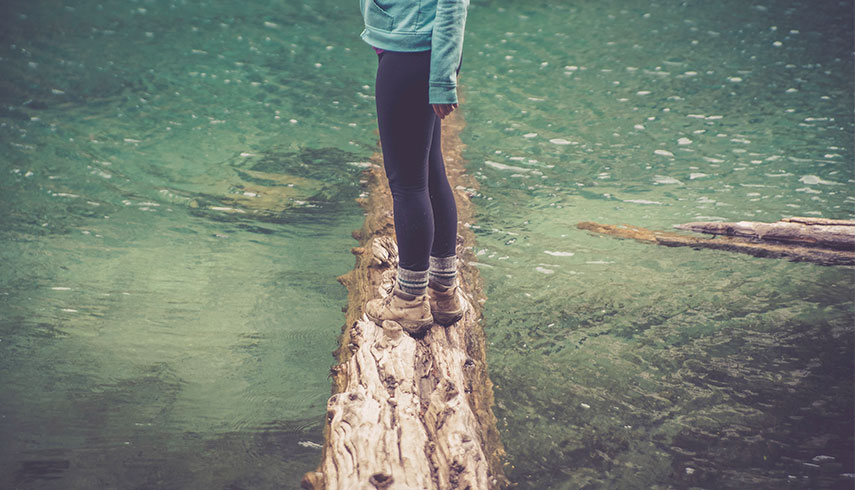 Foto de mulher a equilibrar-se num tronco na água